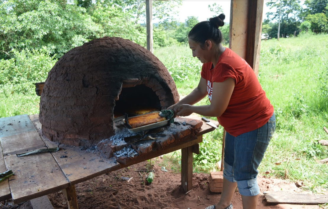 A woman from Arsenio Vazquez removes a dish of Paraguayan soup from a “tatakua” (traditional clay oven), made from corn cultivated by the community. Photo by Inés Franceschelli