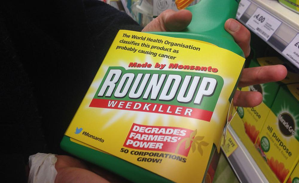 Bottle of Roundup with added label warning, "degrades farmers' power".