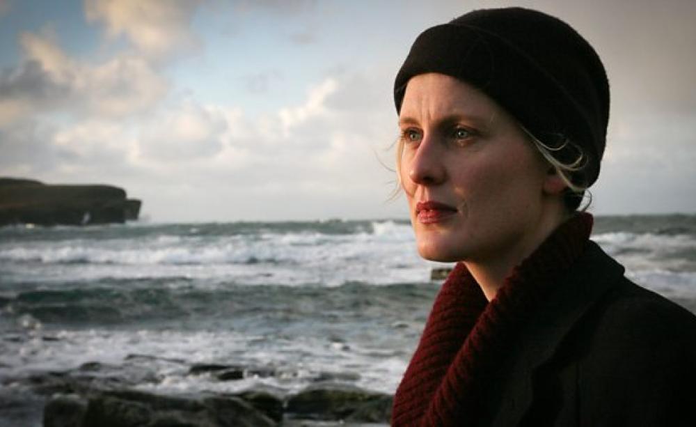 Amy Liptrot with cliffs and sea in the background