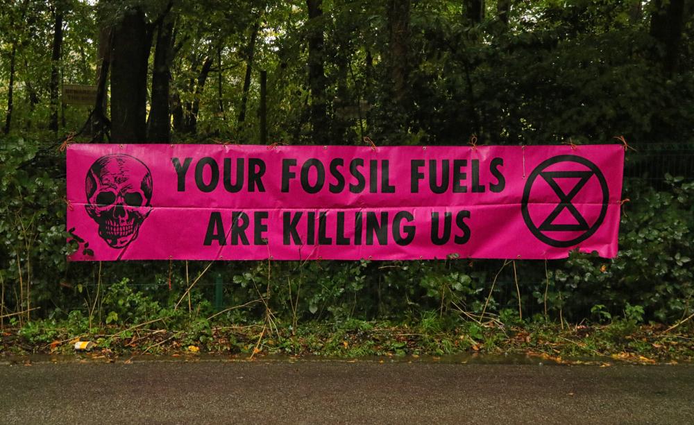 Banner outside oil drilling site that states "Your fossil fuels are killing us"