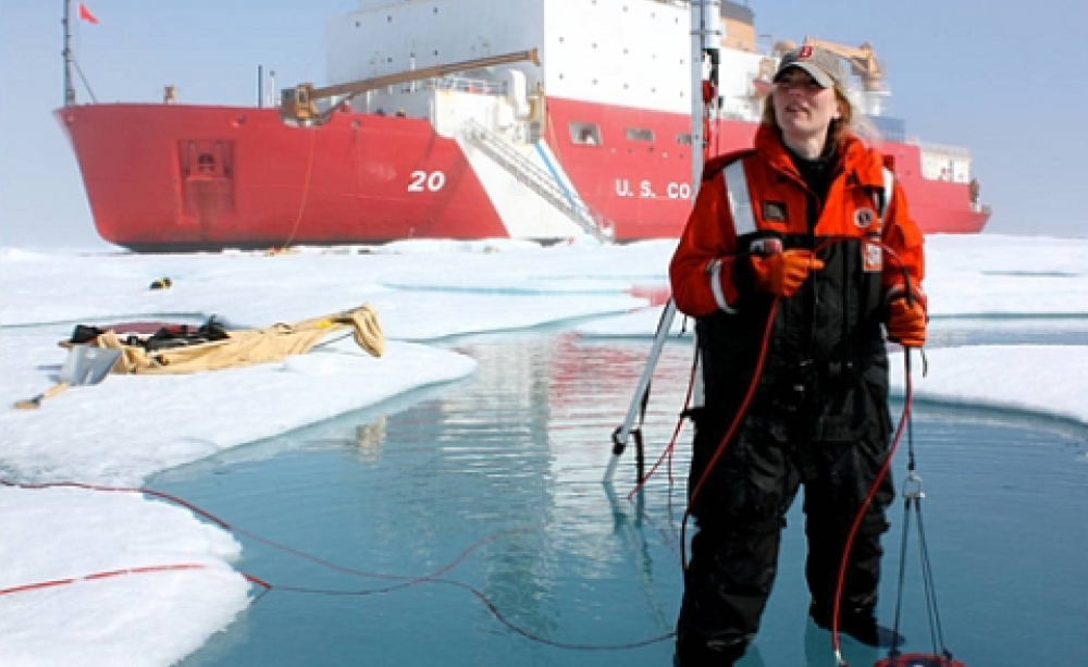 ICESCAPE scientist Karen Frey taking optical measurements in a melt pond, with US Coast Guard Cutter Healy. Photo: NASA's Goddard Space Flight Center / Kathryn Hansen.