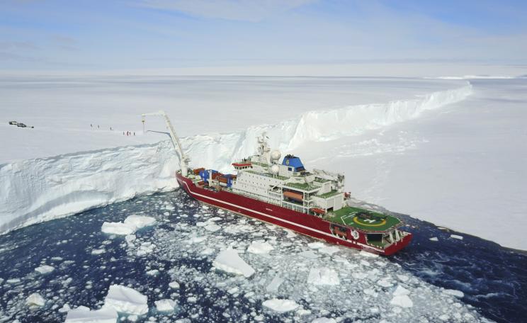 A big boat by a lot of ice. 