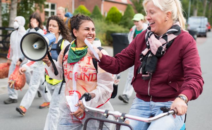 young smiling climate activist woman giving a folder to older smiling lady on a bicycle