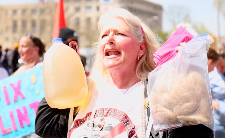 Protester in Flint holding brown water and hair