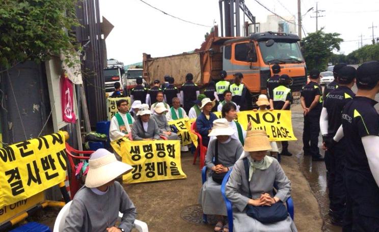 Police escort construction traffic through the gate of the naval base now under construction. Photo: No Naval Base / Facebook.