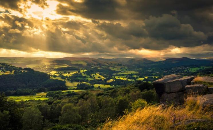 Sun breaking through the clouds over the Derwent Valley, Peak District, UK with the village of Hatersage in the distance. Photo: Richard Walker via Flickr (CC BY).