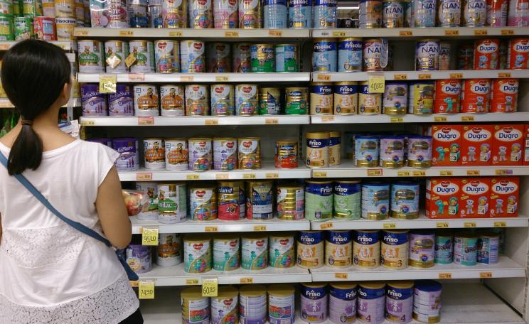 A woman shopping for infant formula at a supermarket in Singapore scans the many different varieties on offer.